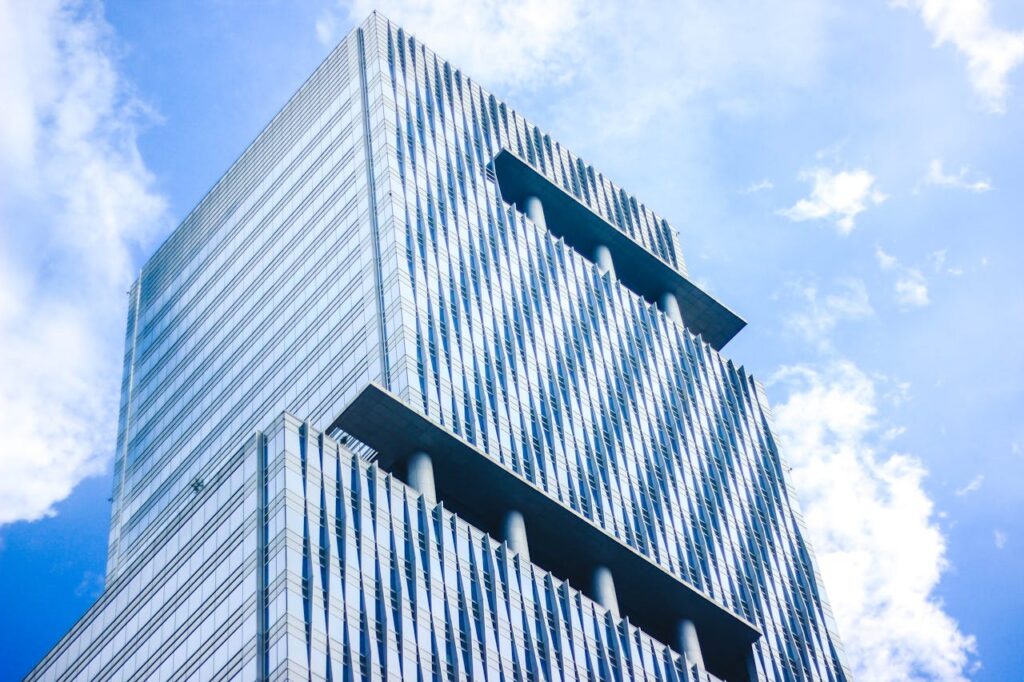pexels photo 358790 Low angle view of a modern glass skyscraper with distinctive architectural design against a vibrant blue sky.