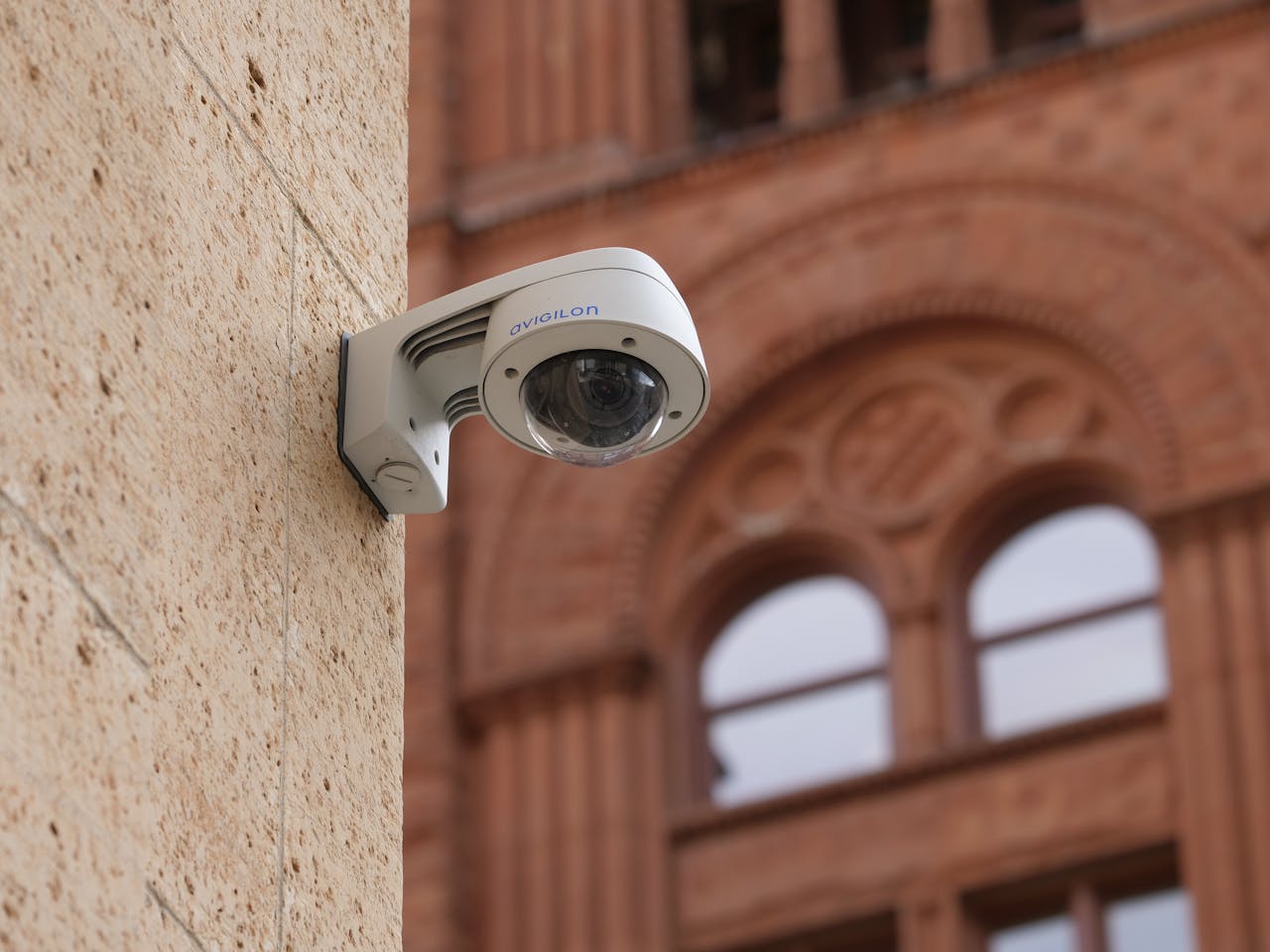 services-01 Wall-mounted dome security camera on a city building, enhancing public safety.