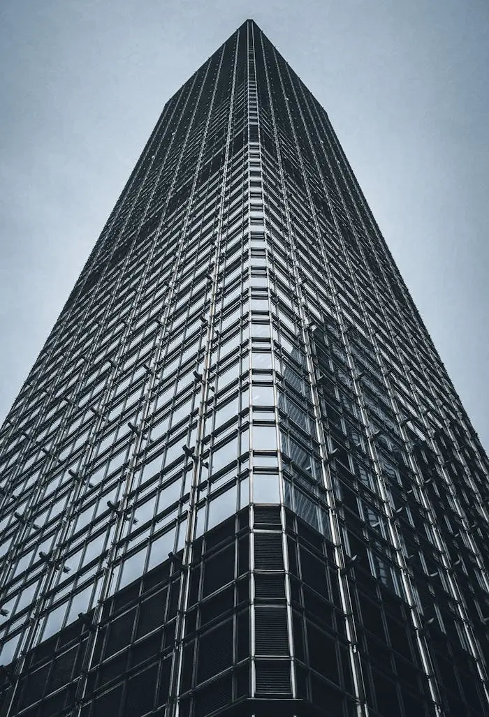 Low-angle view of a modern skyscraper in Hong Kong against a clear sky, emphasizing urban architecture.